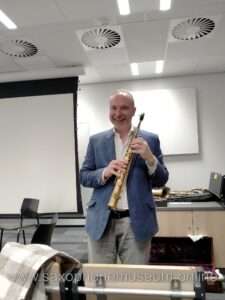 A photograph showing Andreas van Zoelen with a Soprano saxophone, wearing a blue jacket and smiling. 