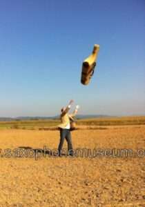 photo of the saxophone case being thrown up in a field of dirt